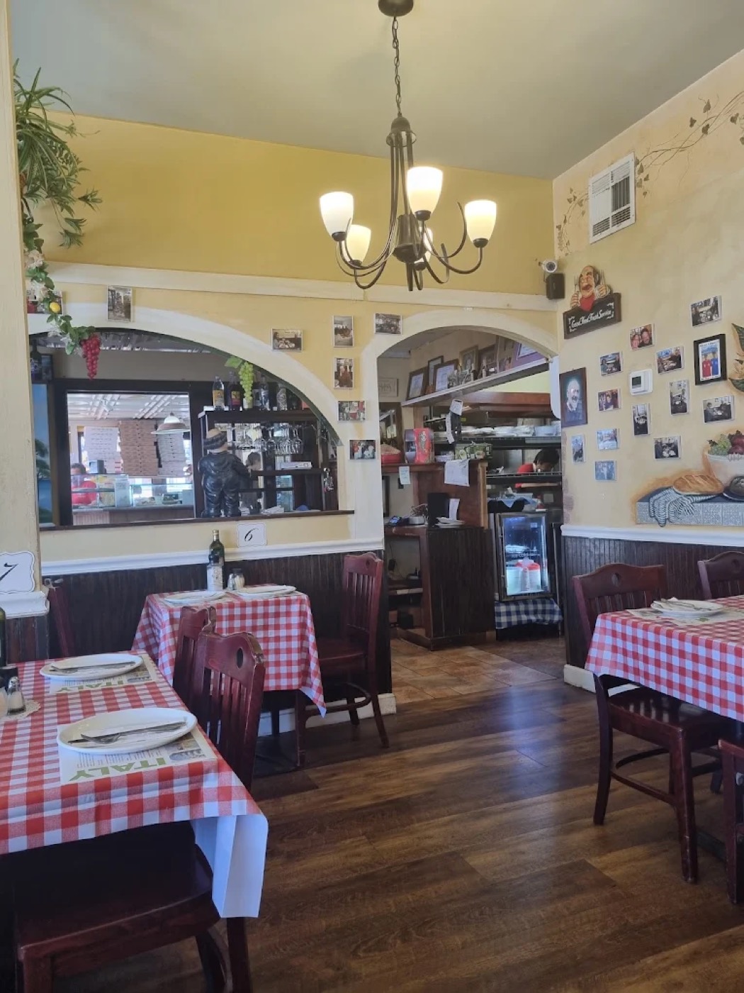 Casa Mia dining room with red checkered tablecloths, wood chairs, and a chandelier.