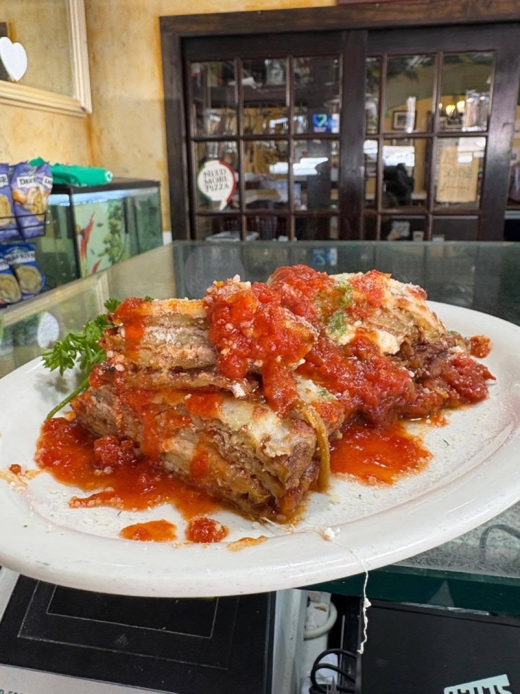 A tall slice of meat lasagna with tomato sauce.