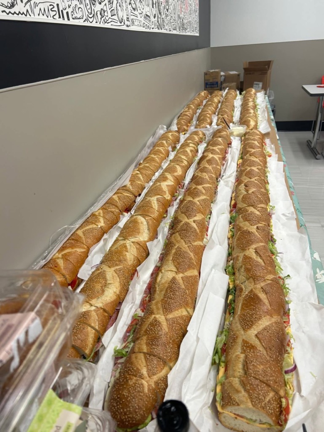 A long row of sesame party subs prepared for catering.