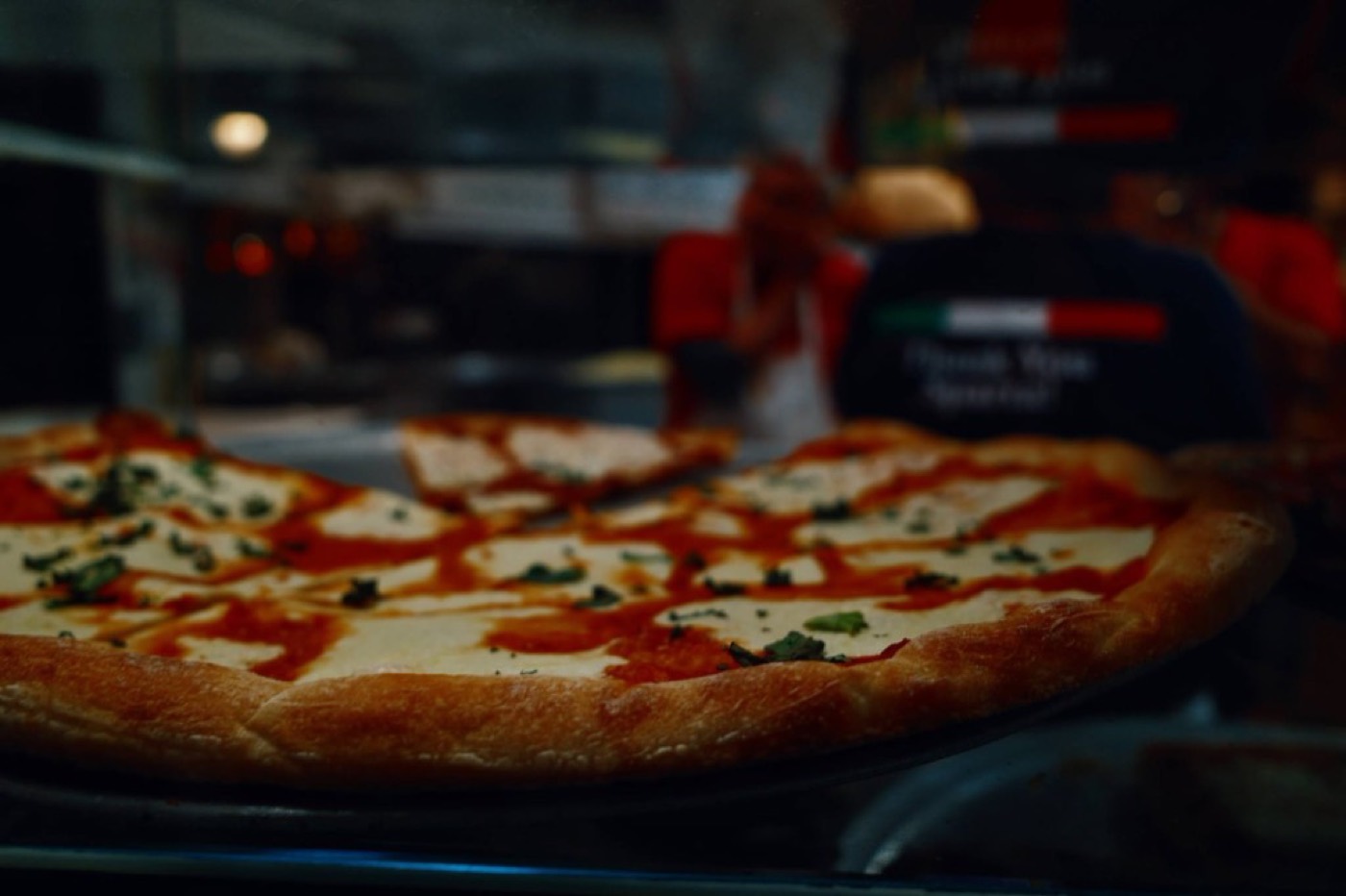 A cheese pizza with basil waiting in the Casa Mia display case.