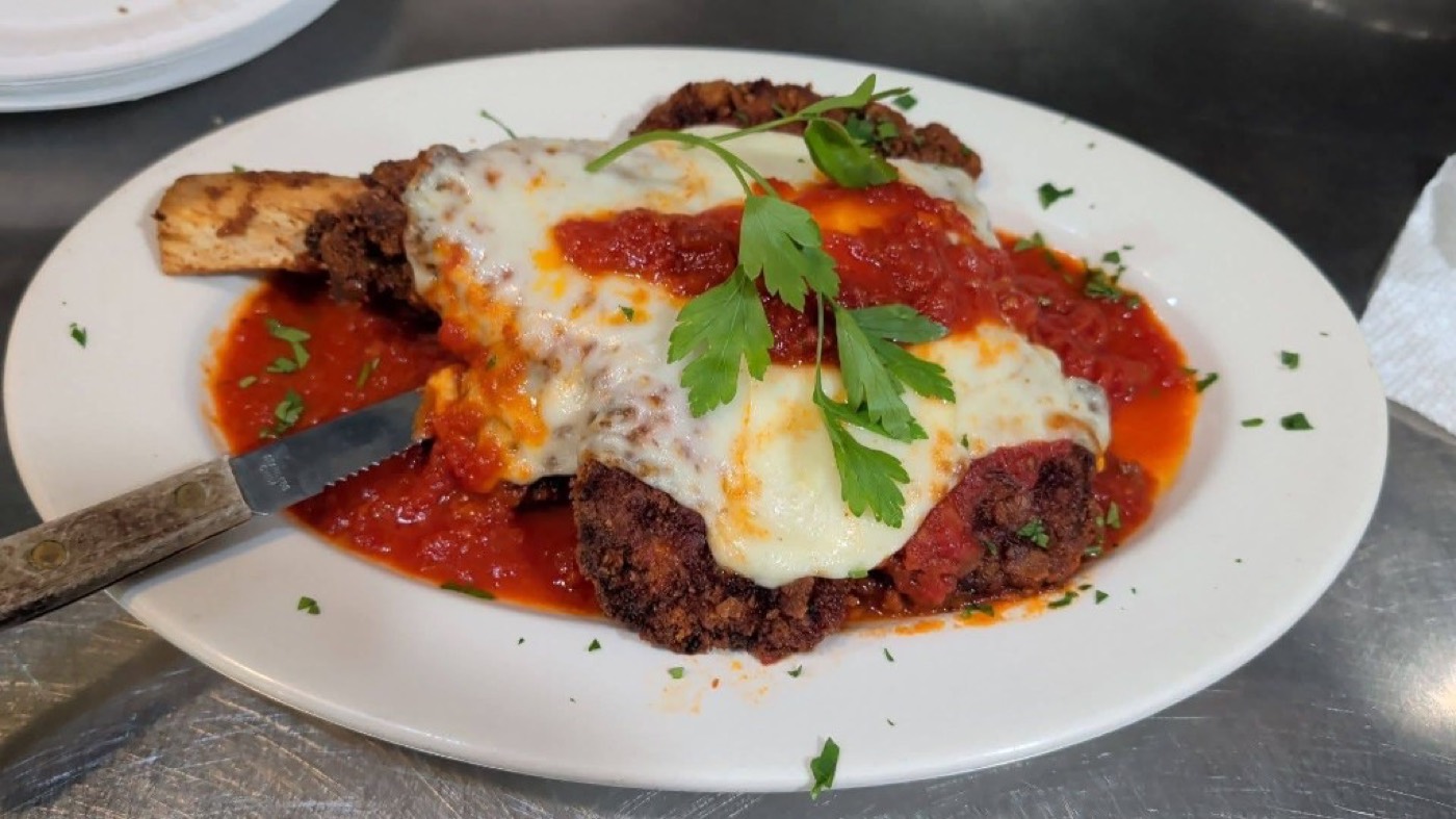 Bone-in veal parmigiana with melted mozzarella, tomato sauce, and parsley.